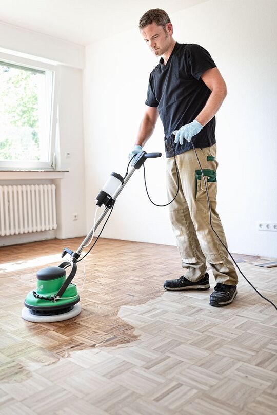 El artesano masajea el 2K Wood Oil Osmo 2K en la superficie de la madera con el FloorXcenter.