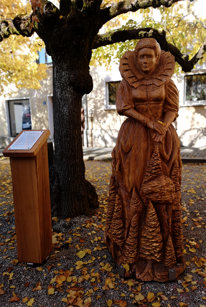 Una hermosa escultura femenina de madera al aire libre bajo un árbol