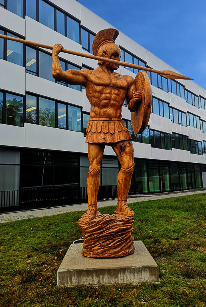 Escultura de madera de Theresia Hoffmann de un soldado romano delante de un edificio